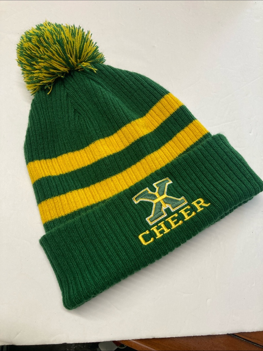 Saint Xavier High School "X Cheer" beanie with a green and gold pom pom.